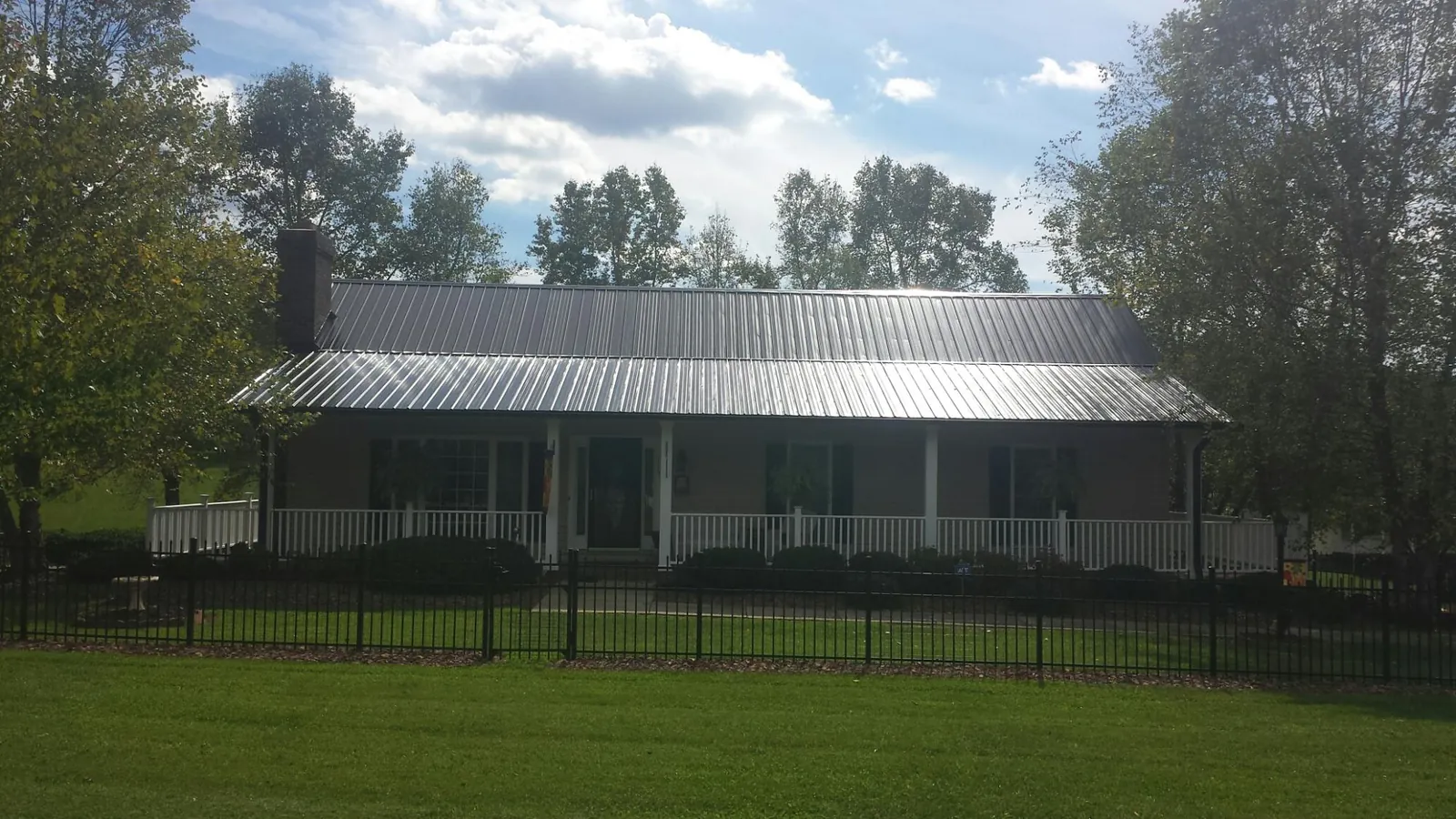 Gray metal roof on a brick ranch with a full width front porch — Gutter Guard Installation work by our crew in Bunker Hill